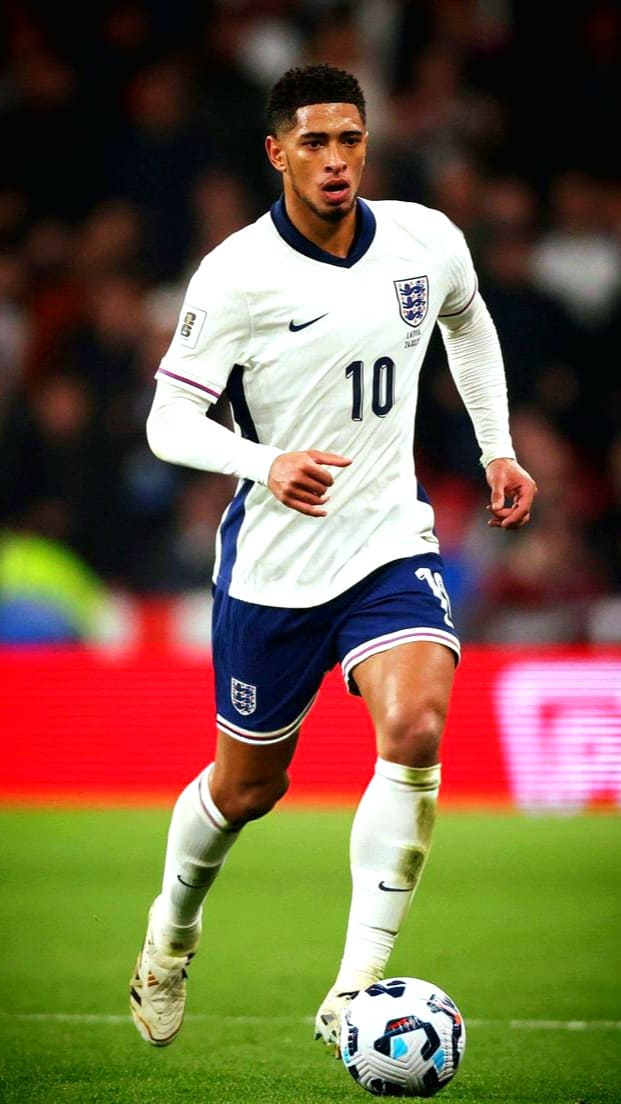 A male soccer player in a white England jersey with number 10 is running on the field, focusing on controlling the ball at his feet during a match, as fans watch live through IPTV Latvia.