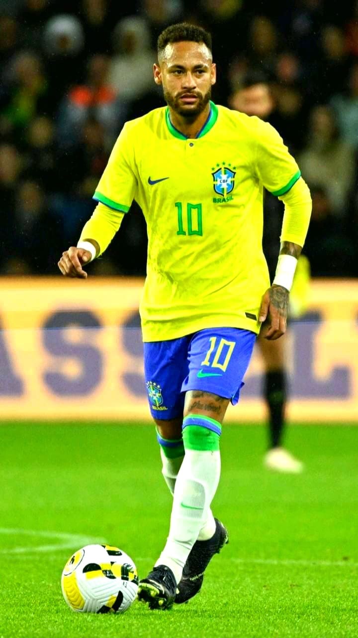 A soccer player in a yellow Brazil jersey with number 10 controls the ball on a field during a match, with blurred players and spectators in the background—perfect action to watch live through IPTV Latvia.